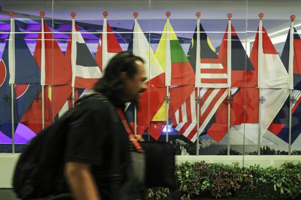 
              A journalist walks past ASEAN member country flags at the Suntec Convention Centre during the 33rd ASEAN summit in Singapore, Monday, Nov. 12, 2018. (AP Photo/Yong Teck Lim)
            