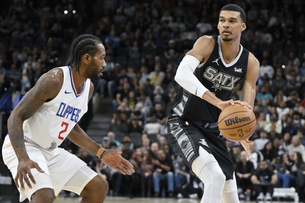 San Antonio Spurs' Victor Wembanyama, right, looks to pass around Los Angeles Clippers' Kawhi Leonard during the first half of an NBA basketball game Wednesday, Nov. 22, 2023, in San Antonio. (AP Photo/Darren Abate)