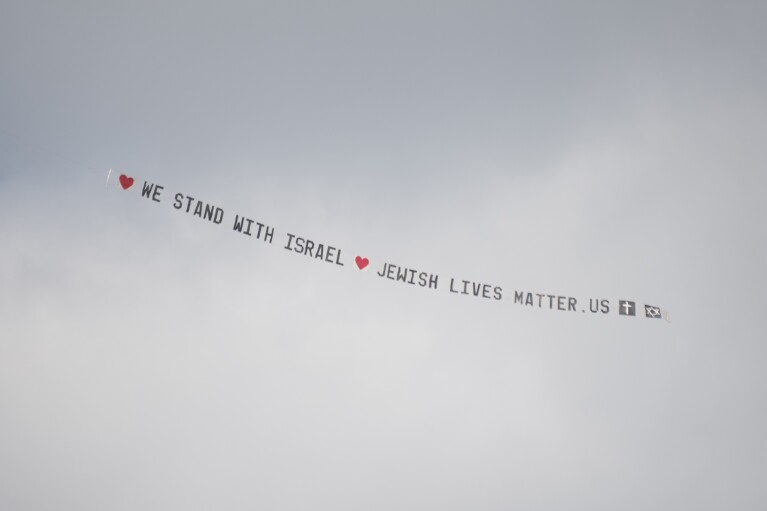 A plane bearing a banner that reads "We stand with Israel jewishlivesmatter.us" flies overhead before the University of Michigan's Spring 2024 Commencement Ceremony at Michigan Stadium in Ann Arbor, Mich., on Saturday, May 4, 2024. (Katy Kildee/Detroit News via AP)