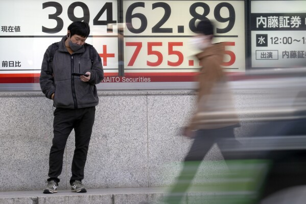 FILE - A person stands in front of an electronic stock board showing Japan's Nikkei 225 index at a securities firm Monday, March 18, 2024, in Tokyo. Shares are mixed in Asia after the Bank of Japan hiked its benchmark interest rate for the first time in 17 years, ending a longstanding negative rate policy.(AP Photo/Eugene Hoshiko, File)