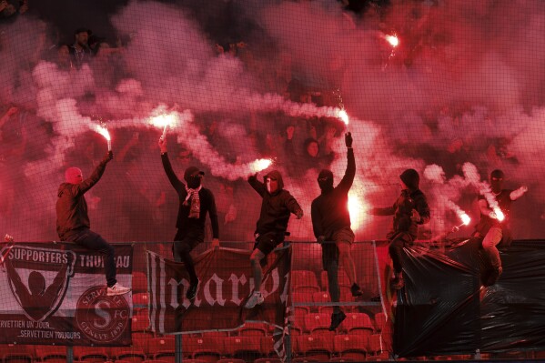 Servette's supporters light smoke flares during the UEFA Champions League second qualifying round first-leg soccer match between Switzerland's Servette FC and Belgium's KRC Genk, at the Stade de Geneve stadium, in Geneva, Switzerland, Tuesday, July 25, 2023. (Salvatore Di Nolfi/Keystone via AP)