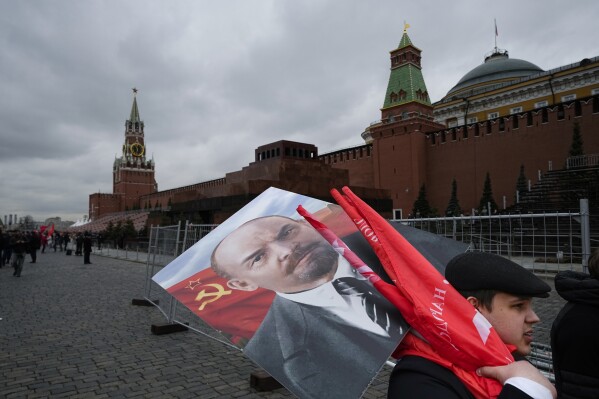 Russian Communists carry a portrait of Vladimir Lenin, the founder of the Soviet Union, and red flags after visiting his mausoleum marking the 152nd anniversary of his birth in Red Square in Moscow, Russia, on Friday, April 22, 2022. (AP Photo/Alexander Zemlianichenko, File)