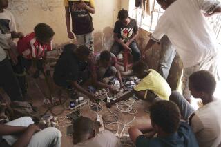 People gather at the home of a volunteer, where they can charge their mobile phones, in Khartoum, Sudan, Thursday, May 25, 2023. The fighting between Sudan’s military and a powerful paramilitary force has displaced more than 1.3 million people, the U.N. migration agency said Wednesday. (AP Photo)