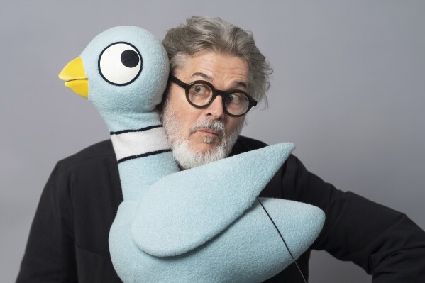 Author Mo Willems poses with The Pigeon, a character in his children's books, on April 22, 2025, in New York. (AP Photo/Gary Gerard Hamilton)