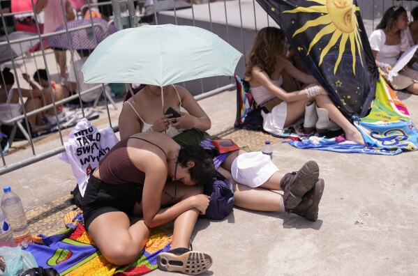 Taylor Swift fans wait for the doors of Nilton Santos Olympic stadium to open for her Eras Tour concert amid a heat wave in Rio de Janeiro, Brazil, Saturday, Nov. 18, 2023. A 23-year-old Taylor Swift fan died at the singer's Eras Tour concert in Rio de Janeiro Friday night, according to a statement from the show's organizers in Brazil. (AP Photo/Silvia Izquierdo)