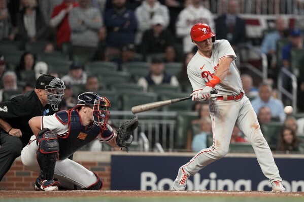 Philadelphia Phillies catcher J.T. Realmuto (10) reaches on catcher interference by Atlanta Braves catcher Sean Murphy during the eighth inning of Game 1 of a baseball NL Division Series, Saturday, Oct. 7, 2023, in Atlanta. (AP Photo/Brynn Anderson)