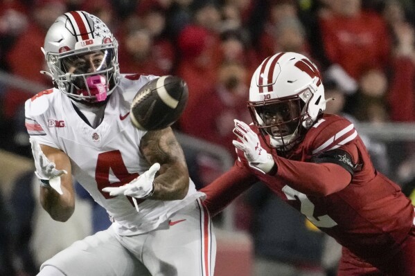 Ohio State's Julian Fleming (4) catches a pass in front of Wisconsin's Ricardo Hallman (2) during the first half of an NCAA college football game Saturday, Oct. 28, 2023, in Madison, Wis. (AP Photo/Morry Gash)