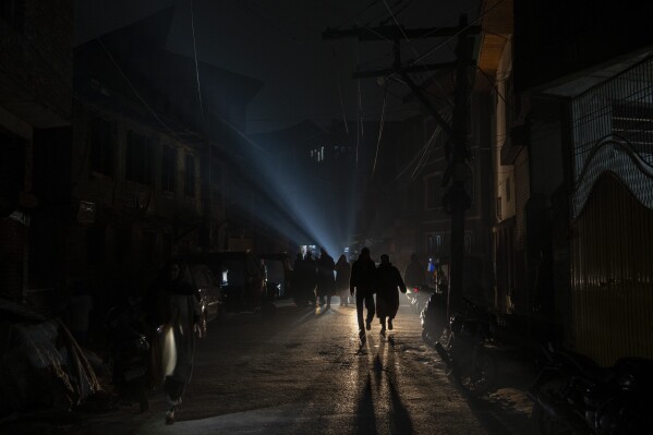 FILE- People walk during a power outage on a cold evening in Srinagar, Indian controlled Kashmir, Wednesday, Dec. 27, 2023. The subzero temperatures in Kashmir, a disputed region between India and Pakistan that has been marred by decades of conflict, also coincide with frequent power cuts. It is one of the idyllic valley's long-standing, unresolved crises. (AP Photo/Dar Yasin, File)