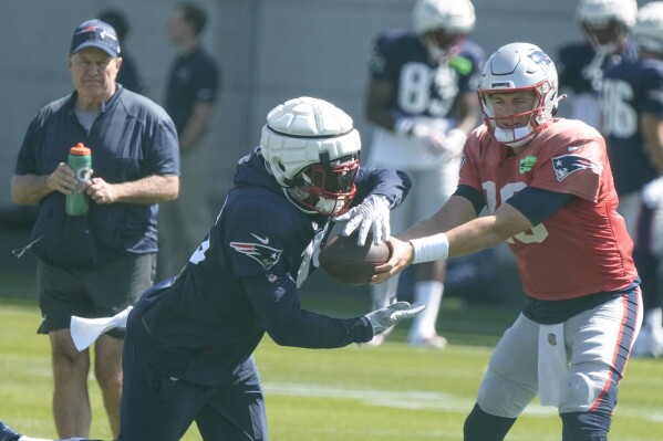 New England Patriots' Ezekiel Elliott takes a handoff from quarterback Mac Jones during practice for NFL football training camp Wednesday, Aug. 16, 2023, in Green Bay, Wis. (AP Photo/Morry Gash)