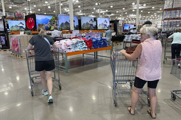 File - Shoppers push carts into a Costco warehouse Friday, Aug. 4, 2023, in Thornton, Colo. A surge in U.S. consumer spending is fueling economic growth, reflecting a resilience among households that has confounded economists, Federal Reserve officials and even the sentiments that Americans themselves have expressed in surveys.(AP Photo/David Zalubowski, File)