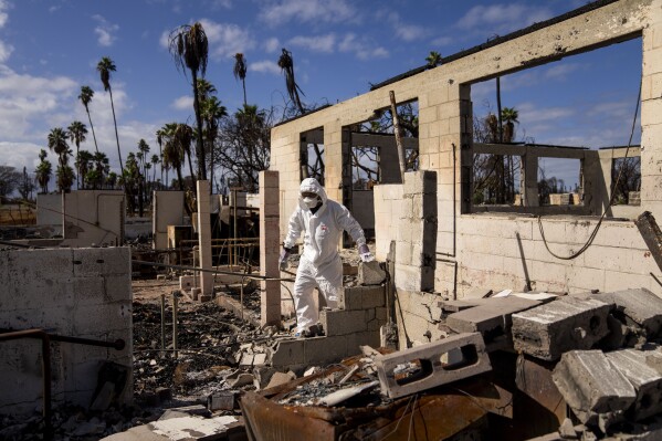 FILE - The Rev. Ai Hironaka, resident minister of the Lahaina Hongwanji Mission, walks through the grounds of his temple and residence destroyed by wildfire, Dec. 7, 2023, in Lahaina, Hawaii. The latest calculations from several science agencies Friday, Jan. 12, 2024, all say that global average temperatures for 2023 shattered existing heat records. (AP Photo/Lindsey Wasson, File)