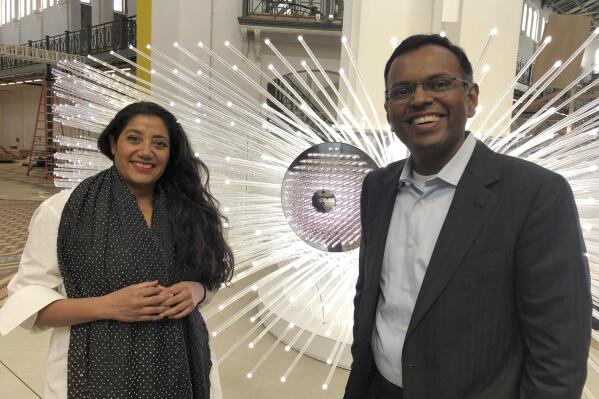 This Oct. 27, 2021, photo shows, from left, artist Suchi Reddy and Swami Sivasubramanian, VP of Amazon Machine Learning at Amazon Web Services, in front of the interactive artwork "me + you" in Washington, D.C. The sculpture uses machine learning to interpret viewers' expressions about the future and incorporate them into the artwork. It is a featured piece of art in the exhibit Futures, which will welcome visitors to the Smithsonian's Arts and Industries Building for the first time in 20 years when the exhibition opens. (AP Photo/Matthew Barakat)