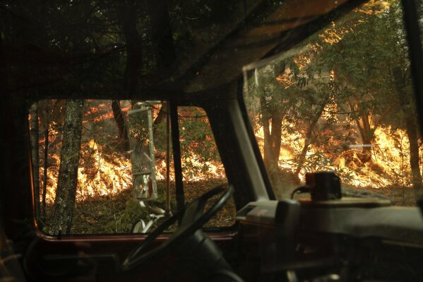 
              A wildfire burning along the Highway 29 is seen through a fire truck Thursday, Oct. 12, 2017, near Calistoga, Calif. More than 8,000 firefighters are battling the blazes and additional manpower and equipment was pouring in from across the country and as far as Australia and Canada. (AP Photo/Jae C. Hong)
            