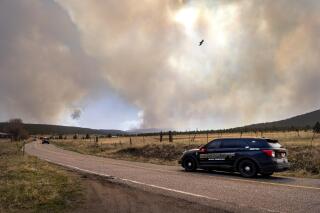 San Miguel County Sheriff's Officers patrol N.M. 94 near Penasco Blanco, N.M. as the Calf Fire burns near by Friday, April 22, 2022. Destructive Southwest fires have burned dozens of homes in northern Arizona and put numerous small villages in New Mexico in the path of danger, as wind-fueled flames chewed up wide swaths of tinder dry forest and grassland and towering plumes of smoke filled the sky. (Eddie Moore/The Albuquerque Journal via AP)