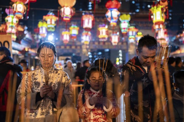 Worshippers pray as they burn their first joss sticks at a temple to welcome in the Lunar New Year of the Dragon in Hong Kong, Friday, Feb. 9, 2024. (AP Photo/Louise Delmotte)