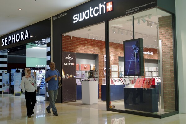 A Malay couple walking pass Swatch outlet at a shopping mall in Putrajaya, Malaysia Thursday, Aug. 10, 2023. Malaysia's government said Thursday that all Swatch products that contain lesbian, gay, bisexual, transgender or queer elements — including watches, wrappers and boxes — were banned, warning that anyone found with one could be jailed for up to three years. (AP Photo/Vincent Thian)