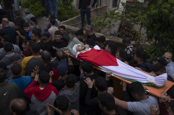 Mourners carry the body of Jehad Abu Alia during his funeral in the West Bank village of al-Mughayyir, Saturday, April 13, 2024. Israel's army says the body of a missing Israeli teen has been found in the occupied West Bank after he was killed in a "terrorist attack." The disappearance of 14-year-old Binyamin Achimair sparked a large attack by settlers on a Palestinian village on Friday and Saturday. (AP Photo/Nasser Nasser)