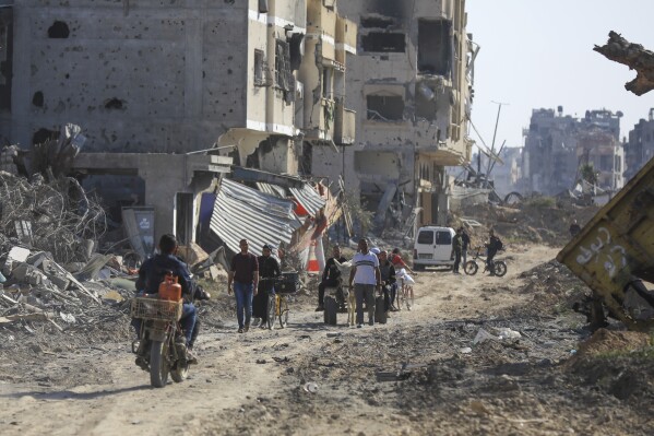 Palestinians walk amid the devastation caused by the Israeli air and ground attack after their withdrawal from Khan Yunis, southern Gaza Strip, Sunday, April 7, 2024. (AP Photo/Ismael Abu Dayyah)