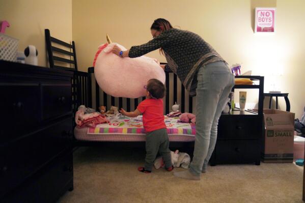 Lauren Hackney plays with her 1-year-old daughter during a supervised visit at their apartment in Oakdale, Pa., on Thursday, Nov. 17, 2022. The Hackneys’ daughter was taken from their custody at 8 months old when the couple brought her to the children's hospital in Pittsburgh after having difficulty feeding her. They believe hospital staff alerted the Allegheny County Department of Human Services because the baby was severely dehydrated and malnourished. (AP Photo/Jessie Wardarski)