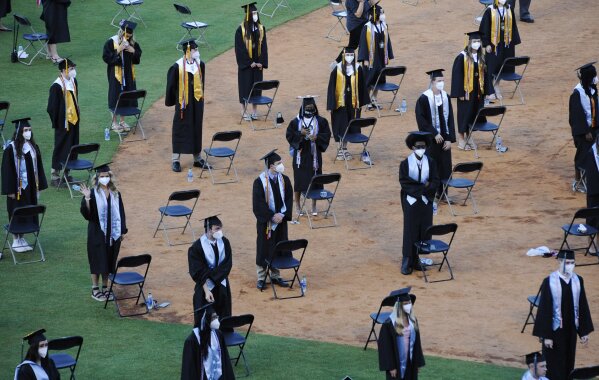 Seniors from Spain Park High School stand on a baseball field at a socially distanced graduation ceremony in Hoover, Ala., Wednesday, May 20, 2020. Health officials say usual graduation ceremonies could endanger the public health by promoting the spread of disease. But school officials say they're using social distancing guidelines and abiding by state health rules. (AP Photo/Jay Reeves)