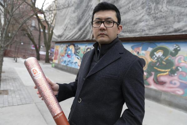 Kamaltürk Yalqun holds the aluminium Olympics torch he carried at the 2008 Beijing Olympic Games at the age of 17, on Friday, Jan. 28, 2022, in Boston. The decade after the Games saw Beijing impose policies on his region of Xinjiang that split apart his family and Uyghur community. Today, he is an activist in the United States calling for a boycott of the 2022 Winter Games, which will see the Olympic flame returned to Beijing. (AP Photo/Michael Dwyer)