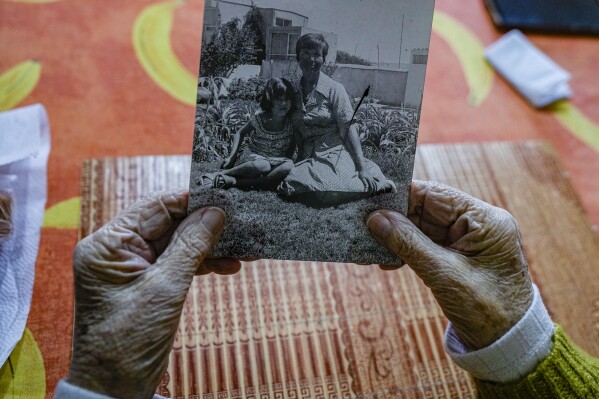 Eliana Rodríguez holds a photograph of herself with her daughter Yelena Monroy at home in La Serena, Chile, Friday, Sept. 1, 2023. The photograph was taken one year after they were released from a detention center where Rodriguez and her two young daughters were imprisoned for over a year during the dictatorship of Gen. Augusto Pinochet, who was brought to power in Chile after a military coup in September 1973. (AP Photo/Esteban Felix)