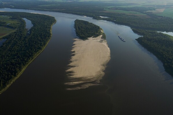 This aerial photo shows shows a tugboat with barges navigating around a sandbar during a period of low water level in the Mississippi River near the Louisiana State Penitentiary in West Feliciana Parish, La., Friday, July 21, 2023. (AP Photo/Gerald Herbert)
