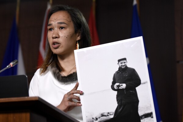 MP Mumilaaq Qaqqaq holds a photo of Joannes Rivoire during a news conference on Parliament Hill in Ottawa, Ontario, Thursday, July 8, 2021. The Oblates of Mary Immaculate says Rivoire, a priest accused of sexually abusing Inuit children in Nunavut, died after a long illness, Thursday, April 11, 2024. (Justin Tang/The Canadian Press via AP)