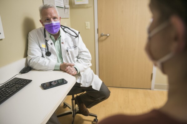 In this photo provided by University of Michigan Health-West, Dr. Lance Owens, chief medical information officer at the university, demonstrates the use of an AI tool on a smartphone in Wyoming, Mich., on Sept. 9, 2021. The software listens to a doctor-patient conversation, documents and organizes it to write a clinical note. (University of Michigan Health-West via AP)