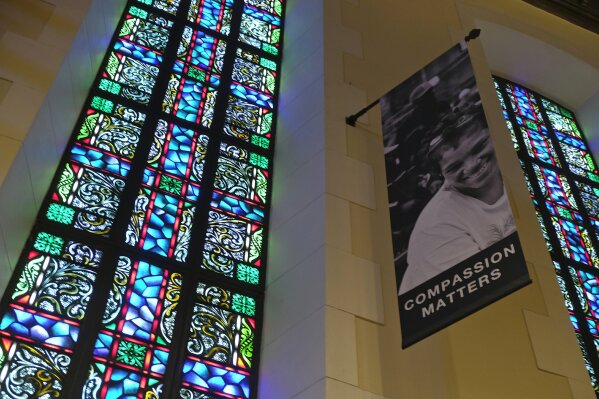 FILE - In this Feb. 12, 2019 file photo, a banner hangs by a stained glass window in the sanctuary at Glide Memorial United Methodist Church in San Francisco. Most Americans don’t typically reach out to religious leaders for guidance, according to a poll from The Associated Press-NORC Center for Public Affairs Research. The poll shows the lack of personal connection with ministers even includes people who identify with a religion, though it’s less prevalent among those most engaged with their faith. (AP Photo/Eric Risberg)