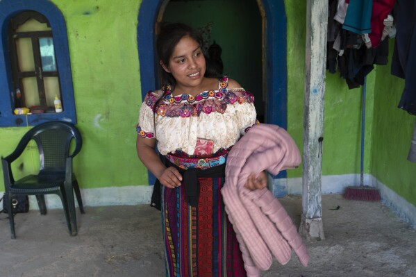 Glendy Aracely Ramírez muestra una chaqueta que compró para su migración planificada a los EE. UU. en su aldea Loma Linda de Comitancillo, Guatemala, el lunes 18 de marzo de 2024. Glendy planea migrar a los EE. UU., a pesar de la muerte de su hija de 23 años. Blanca, su hermana mayor, que murió en su tercer intento de llegar a Estados Unidos, asfixiada junto con otros 50 migrantes en el camión con remolque de un contrabandista en San Antonio, Texas, en junio de 2022. (Foto AP/Moises Castillo)