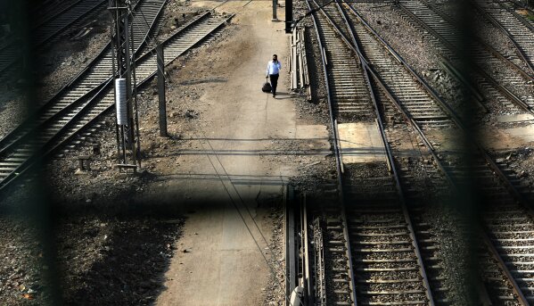 A passenger walks between railway tracks at New Delhi Railway station during a lockdown amid concerns over the spread of Coronavirus, in New Delhi, India, Monday, March 23, 2020. Authorities have gradually started to shutdown much of the country of 1.3 billion people to contain the outbreak. For most people, the new coronavirus causes only mild or moderate symptoms. For some it can cause more severe illness. (AP Photo/Manish Swarup)