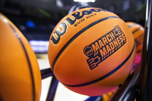 A basketball with a March Madness logo rests on a rack before a First Four game between Illinois and Mississippi State in the NCAA women's basketball tournament, March 15, 2023, in South Bend, Ind. (AP Photo/Michael Caterina, File)