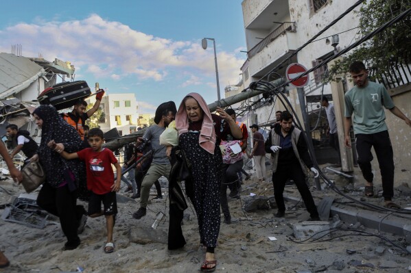 Các gia đình Palestine chạy ra khỏi nhà sau các cuộc không kích của Israel nhắm vào khu vực lân cận của họ ở Thành phố Gaza, trung tâm Dải Gaza, Thứ Ba, ngày 17 tháng 10 năm 2023. (Ảnh AP / Abed Khaled)