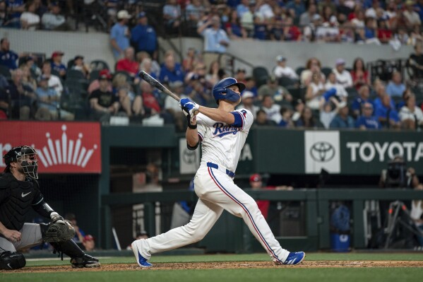 Texas Rangers' Corey Seager hits a two run home run off of Arizona Diamondbacks starting pitcher Ryne Nelson as Arizona Diamondbacks catcher Tucker Barnhart looks on during the fifth inning of a baseball game Wednesday, May 29, 2024, in Arlington, Texas. Ezequiel Duran scored on the play. (AP Photo/Jeffrey McWhorter)