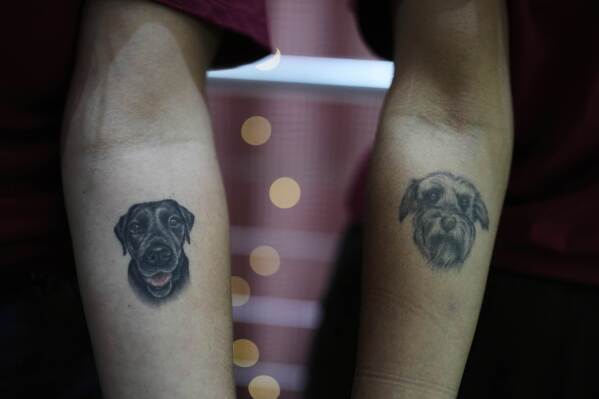 Nadia Onischuk, left, shows the tattoo on her arm depicting her dog Mora, as Nicole Verdier shows her tattoo of her late dog Tadeo, at Chumbis, an artisanal bakery for animals, in Buenos Aires, Argentina, Friday, April 4, 2025. (AP Photo/Natacha Pisarenko)
