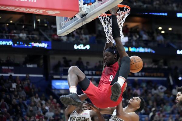 Portland Trail Blazers forward Jerami Grant (9) slam dunks over New Orleans Pelicans guard Trey Murphy III, right, and forward Herbert Jones, left, in the second half of an NBA basketball game in New Orleans, Thursday, Nov. 10, 2022. The Trail Blazers won 106-95. (AP Photo/Gerald Herbert)