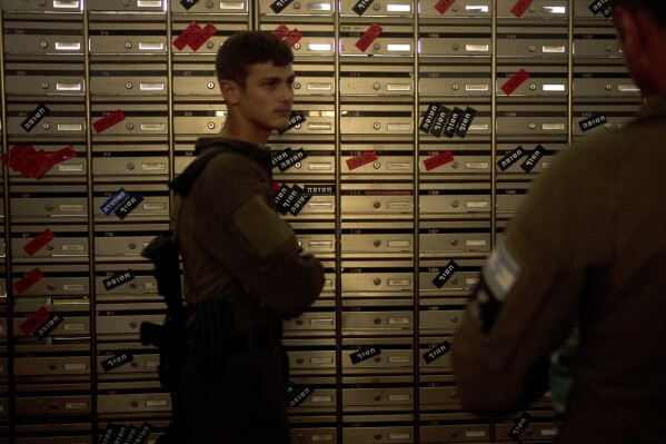 Israeli soldiers visit the mailroom in Kibbutz Nir Oz, where mailboxes are labeled with residents' status - killed (red), kidnapped (black), and released (blue) on Thursday, April 11, 2024, at the communal dining hall during a Passover seder event for hostages held in Gaza, at the kibbutz in southern Israel, where a quarter of all residents were killed or captured by Hamas on Oct. 7, 2023. For many Jews, no matter how observant, Passover is a time to unite with family to eat and drink around what's known as a Seder table, remembering how the Jews persevered through harsh times. But this year, when Passover begins on Monday, many families are torn on how to celebrate, or if it's worth acknowledging at all. (AP Photo/Maya Alleruzzo)