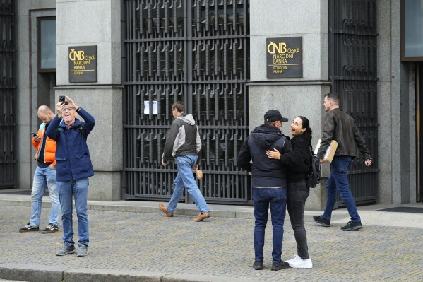 FILE - People stand outside the czech central bank in Prague, Czech Republic, on Nov. 2, 2023. On Wednesday March 20, 2024, the Czech central bank cut its key interest rate for the third straight time on amid falling inflation and an effort to help the economy. The cut by a half-percentage point brought the interest rate down to 5.75%. (AP Photo/Petr David Josek/File)