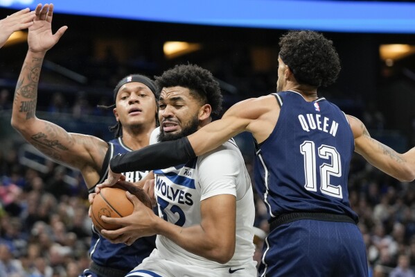 Minnesota Timberwolves center Karl-Anthony Towns, center, makes a moves to get past Orlando Magic forward Paolo Banchero, left, and guard Trevelin Queen (12) during the first half of an NBA basketball game, Tuesday, Jan. 9, 2024, in Orlando, Fla. (AP Photo/John Raoux)