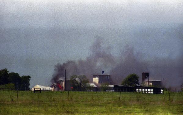 Flames are seen in building to right of tower and smoke billows into sky as the fire first becomes visible at the Branch Davidian compound near Waco, Texas on Monday, April 19, 1993. The compound burned to the ground and the Justice Department said cult members set the fire. (AP Photo/Roberto Borea)