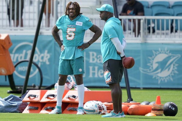 Miami Dolphins cornerback Jalen Ramsey (5) stands with a member of the coaching staff during practice at the NFL football team's training facility, Thursday, July 27, 2023, in Miami Gardens, Fla. (AP Photo/Lynne Sladky)