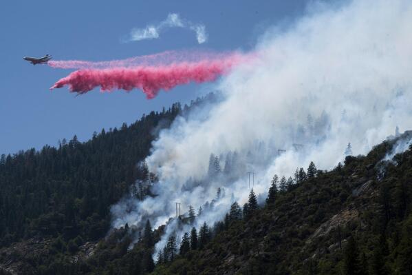 An air tanker drops fire retardant to battle the Dixie Fire in the Feather River Canyon in Plumas County, Calif., Wednesday, July 14, 2021. Residents were warned to be ready to evacuate as a growing wildfire bears down on two remote Northern California communities near a town largely destroyed by a deadly blaze three years ago. The fire that broke out Tuesday afternoon has chewed through more than 1.8 square miles (4.8 square kilometers) of brush and timber near the Feather River Canyon area of Butte County. (Paul Kitagaki Jr./The Sacramento Bee via AP)