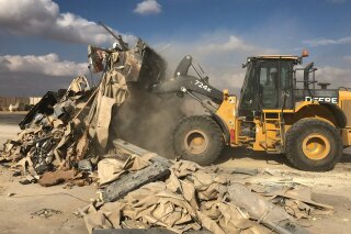 A bulldozer clears rubble and debris at Ain al-Asad air base in Anbar, Iraq, Monday, Jan. 13, 2020. Ain al-Asad air base was struck by a barrage of Iranian missiles in retaliation for the U.S. drone strike that killed atop Iranian commander, Gen. Qassem Soleimani, whose killing raised fears of a wider war in the Middle East. (AP Photo/Qassim Abdul-Zahra)