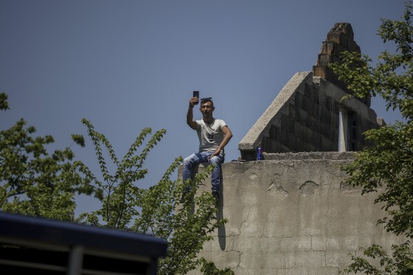 A man watches the bullfights from an abandoned house in Bijelo Polje, Bosnia, Sunday, May 11, 2025. (AP Photo/Armin Durgut)