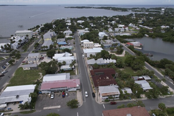 In this photo taken with a drone, businesses are seen along 2nd Street in Cedar Key, Fla., ahead of the expected arrival of Hurricane Idalia, Tuesday, Aug. 29, 2023. Several local residents said they planned to ride out the storm at the Cedar Inn Motel, with red roof, lower left. (AP Photo/Rebecca Blackwell)