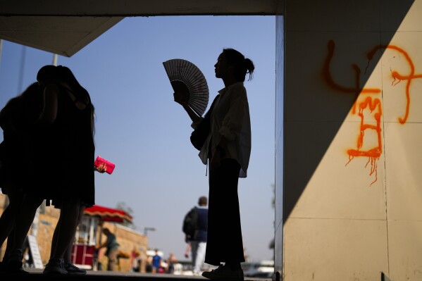 A woman has a break in the shade under Galata bridge on a hot summer day in Istanbul, Thursday, July 13, 2023. (AP Photo/Francisco Seco)