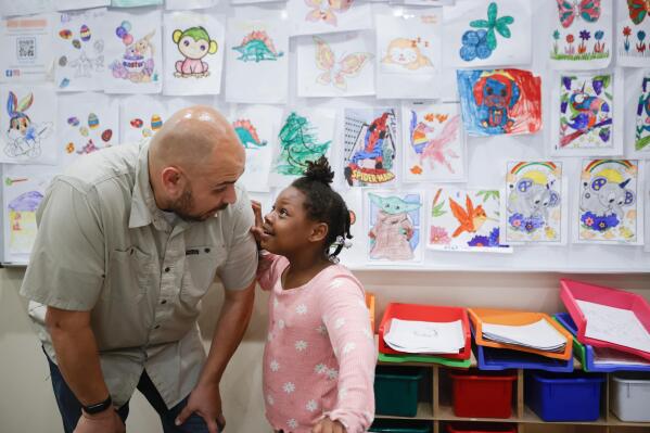 Tim McNeeley, left, speaks with Narekeyla Thomas, 6, during an after-school literacy program in Atlanta on Thursday, April 6, 2023. McNeeley, director of the Atlanta based Pure Hope Project, hosts the daily program for children in kindergarten through fifth grade. (AP Photo/Alex Slitz)