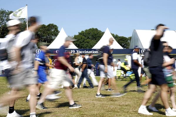 People walk by a COVID-19 vaccination centre on site, during day three of British Open Golf Championship,  at the Royal St George's Golf Club in Sandwich, Kent, England,  Saturday July 17, 2021. (Gareth Fuller/PA via AP)