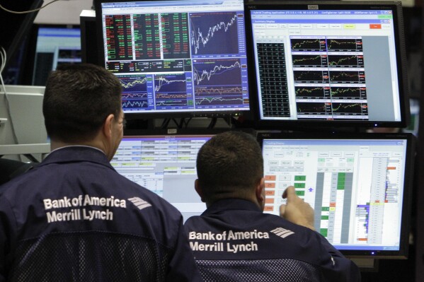 FILE - A pair of Bank of America-Merrill Lynch specialists work at their post on the floor of the New York Stock Exchange Monday, Jan. 10, 2011. Merrill Lynch has agreed to pay nearly $20 million to settle a class-action lawsuit that accuses the Wall Street brokerage giant of racially discriminating against its Black financial advisors. (AP Photo/Richard Drew, File)